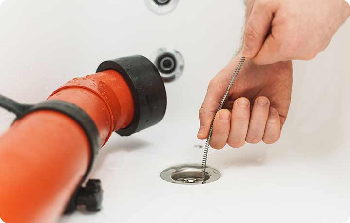 Tip Top Plumbing & Restoration provides reliable drain cleaning services in Broward County, FL. This image clearly illustrates a plumber expertly using specialized drain cleaning equipment to unclog pipes. For prompt plumbing services, contact Tip Top Plumbing at 954-471-4036.