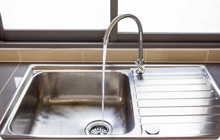 Tip Top Plumbing & Restoration offers professional garbage disposal repair services in Broward County, FL. This image depicts a pristine kitchen sink with running water, representing the reliable plumbing repairs provided by Tip Top Plumbing. For prompt plumbing service, call 954-471-4036.