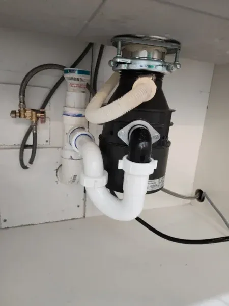 Tip Top Plumbing installs and repairs garbage disposal units in Broward County kitchens, providing professional drain and power connections beneath modern sinks.