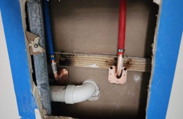 A close-up of a pipe leak repair in progress inside a Broward County home, showing the damaged pipe joint, water stream, and surrounding repair tools. Tip Top Plumbing provides fast, expert leak detection and repair to prevent water damage and restore integrity.