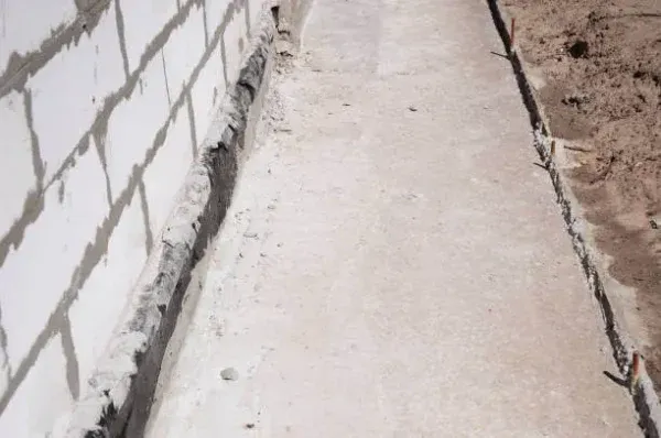 Visual indicators of a potential slab leak in a Florida home—slightly warped flooring and moisture staining along the baseboards, with a moisture detection tool in use. Tip Top Plumbing identifies early warning signs of hidden leaks under the foundation.