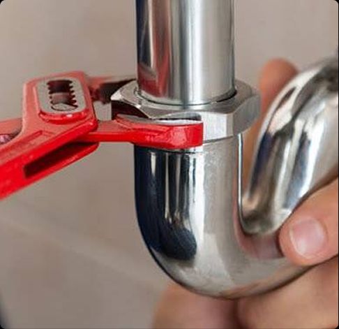Close-up of a plumber tightening a chrome pipe under a sink, representing trusted plumbing services in Franklin Park, FL.