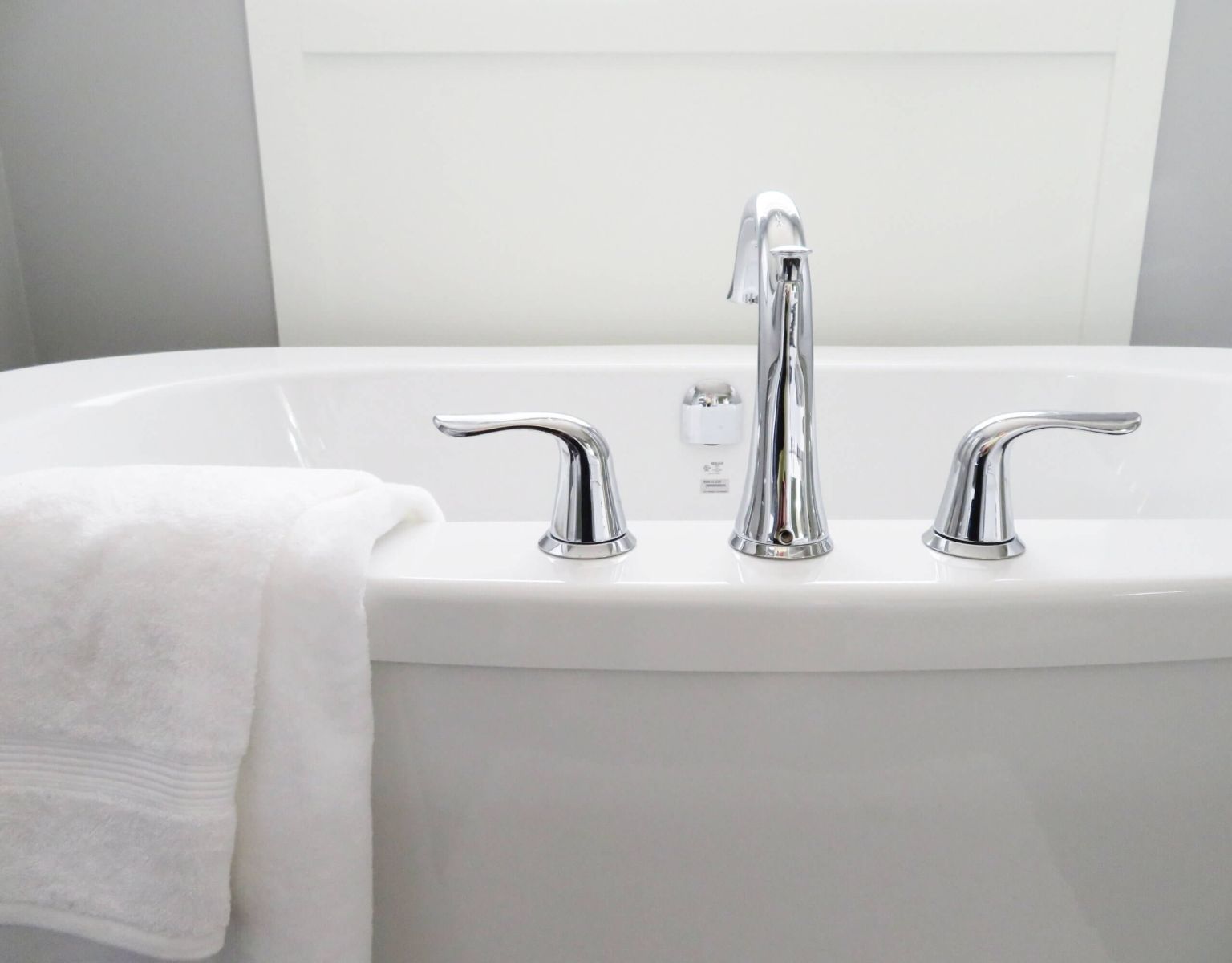 Tip Top Plumbing & Restoration in North Lauderdale FL offers expert bathtub plumbing services. This image shows a modern bathtub with a sleek chrome faucet set and towel.