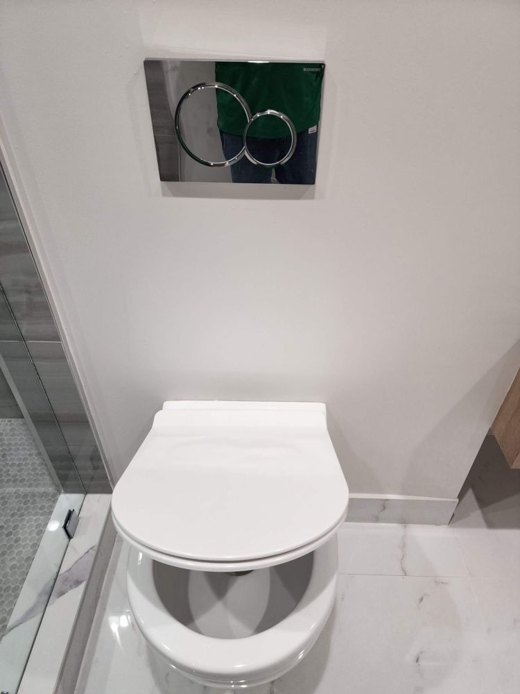 Modern wall-mounted toilet with dual flush panel in a luxury bathroom setting.