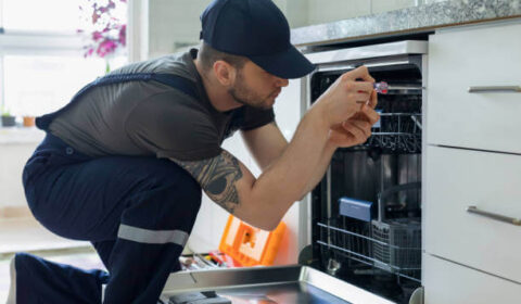 Dishwasher Installation & Repair Services in Miramar, FL Tip Top Plumbing & Restoration technician installing a dishwasher in a modern kitchen in Miramar, FL, with focus on connecting water and drainage lines.
